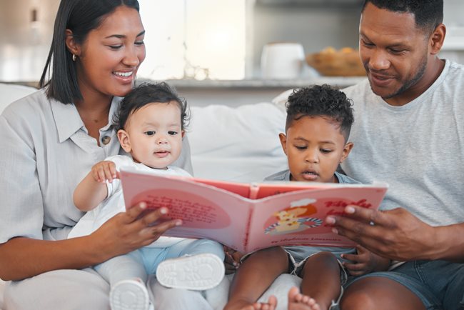 Mamá y papá leyendo a sus dos hijos pequeños