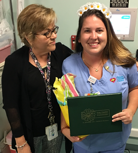 awardee wearing a headband of daisies, daisy award statue, and certificate.