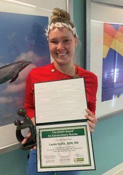 awardee wearing a headband of daisies, daisy award statue, and certificate.