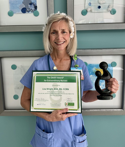 awardee wearing a headband of daisies, daisy award statue, and certificate.