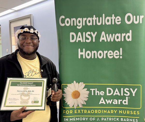 awardee wearing a headband of daisies, daisy award statue, and certificate.