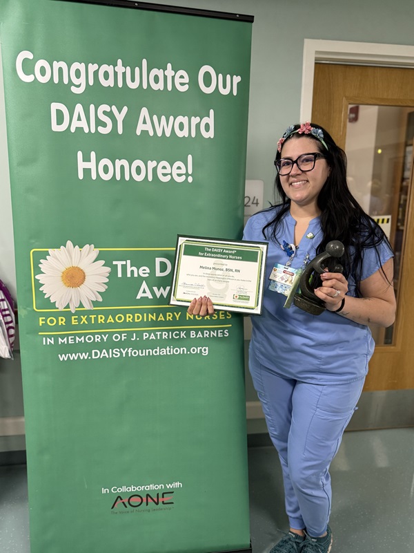awardee wearing a headband of daisies, daisy award statue, and certificate.