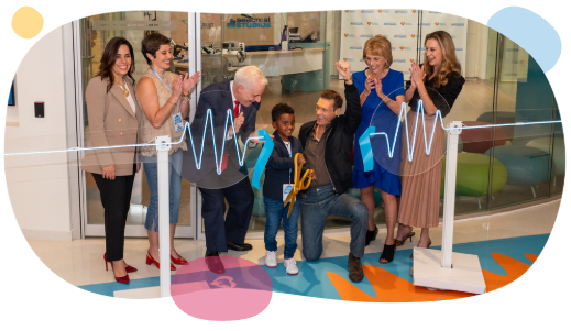 Ryan Seacrest and Matt Love with a patient cutting the ribbon to Seacrest Studios