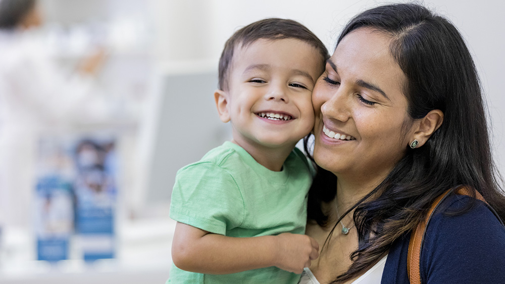 smiling boy held by his mother.