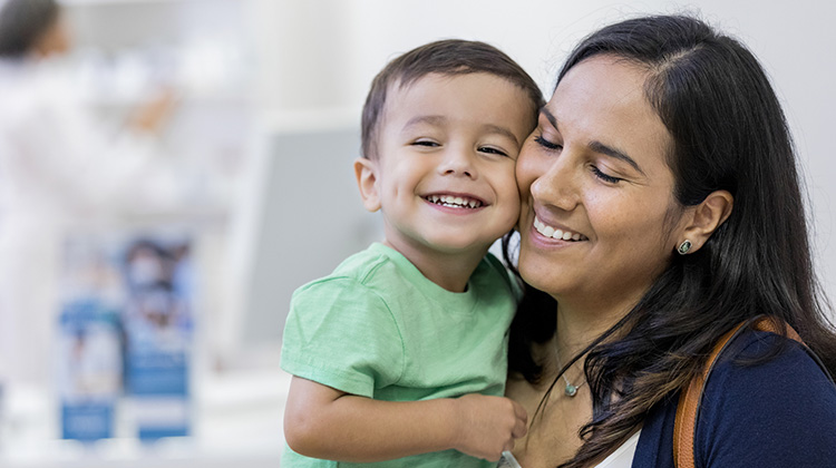 smiling boy held by his mother.