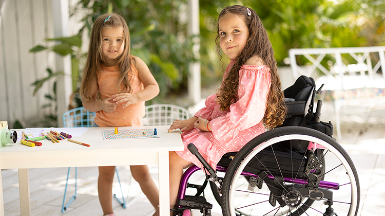 Sofia in her wheelchair playing a game with her sister.