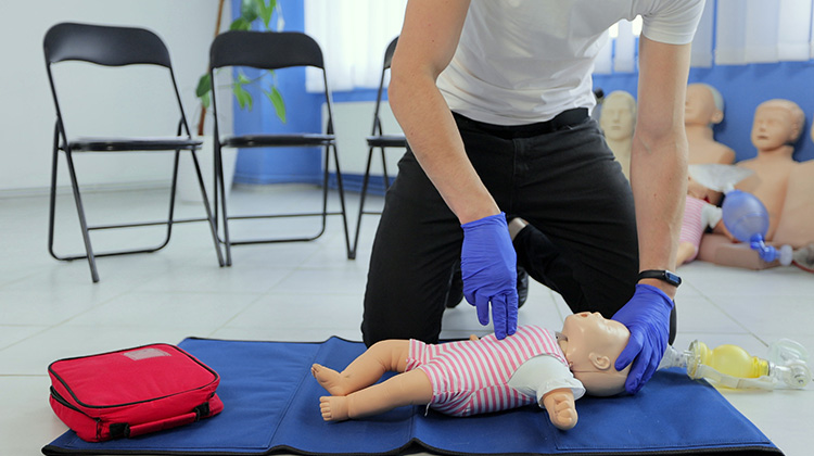 instructor performing CPR on an infant CPR mannequin.
