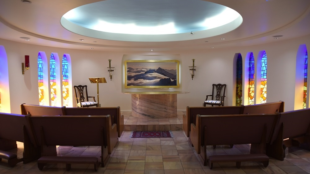 small chapel with altar, stained glass windows and pews.