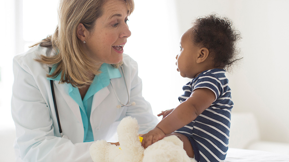 female doctor smiling at seated baby
