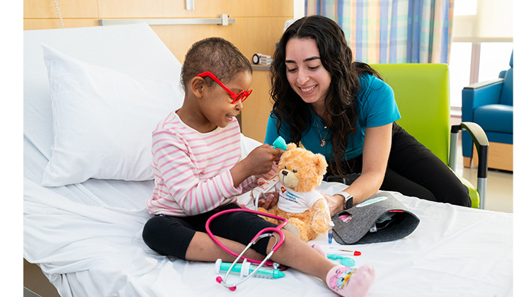 Especialista en Vida Infantil enseñando y jugando con niña en su cuarto de hospital.