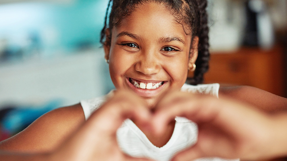 girl making a heart shape with her hands.